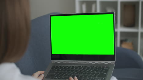Woman-at-Home-Sitting-on-a-Couch-Works-on-a-Laptop-Computer-with-Green-Mock-up-Screen.-Coronavirus-Covid-19-quarantine-remote-education-or-working-concept.-Girl-Using-Computer-Browsing-through